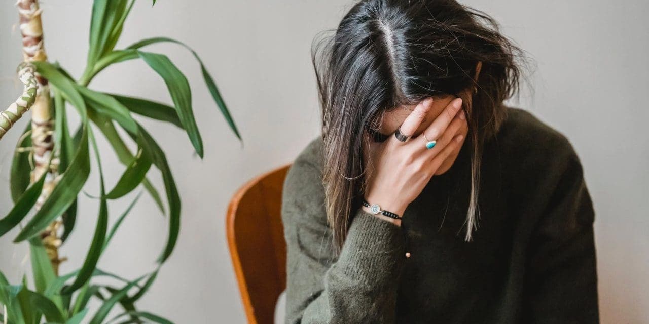 worried young woman covering face with hand